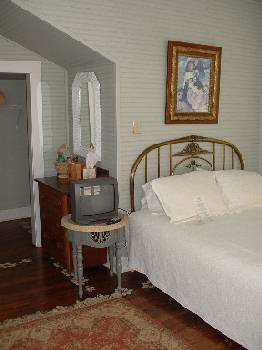 tower room showing queen bed, small tv, antique dresser and nightstand